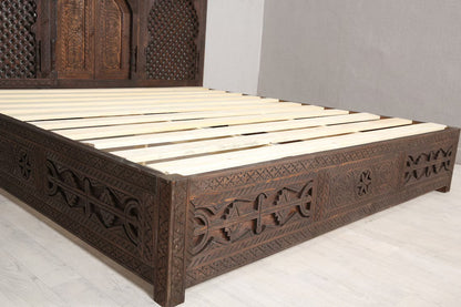 The dark wood finish of a handcrafted Moroccan bed.
