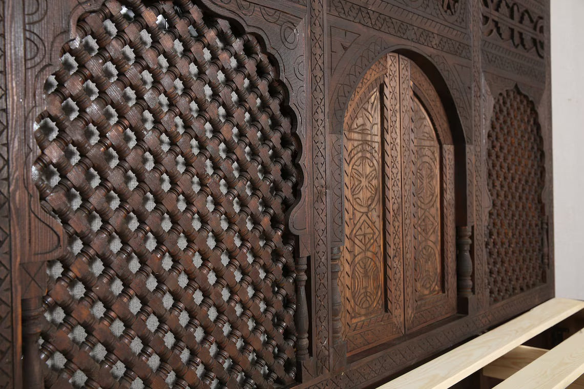 Detail of the arched wooden panel on the headboard of a handcrafted bed.