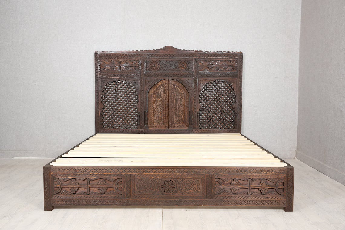 Solid wood bed frame with intricate carvings and a dark wood finish.
