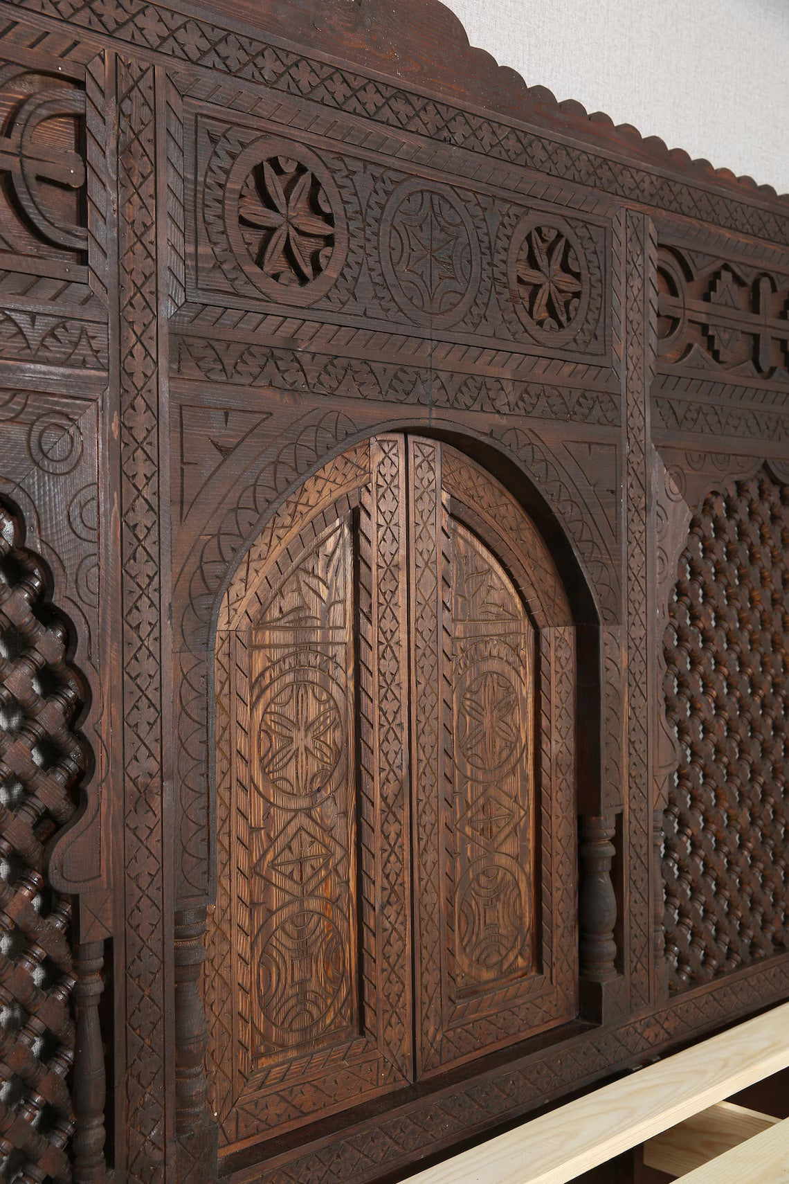 Close-up of the intricate carvings on the headboard of a Moroccan-style wooden bed