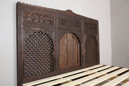 Handcrafted Moroccan-inspired wooden bed with a high headboard.
